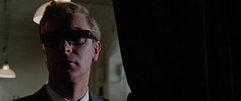Movie still from “The Ipcress File” (1965), directed by Sidney J. Furie – A person wearing a suit and glasses; Close Up shot, Low angle