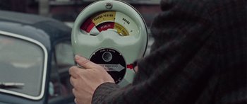 Movie still from “The Ipcress File” (1965), directed by Sidney J. Furie – A person is holding a parking meter in their hand; Extreme Close Up shot, High angle