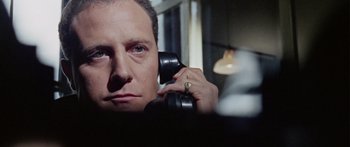 Movie still from “The Ipcress File” (1965), directed by Sidney J. Furie – A man holding a phone up to his ear; Close Up shot, Low angle