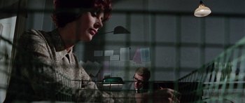 Movie still from “The Ipcress File” (1965), directed by Sidney J. Furie – A man and a woman are looking at each other through a window; Medium shot, Low angle
