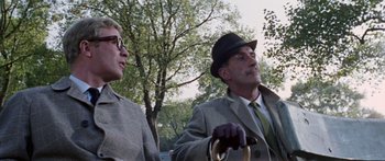 Movie still from “The Ipcress File” (1965), directed by Sidney J. Furie – A man and a woman are standing next to each other holding a steering wheel; Medium shot, Low angle