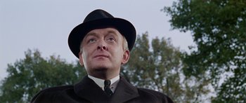 Movie still from “The Ipcress File” (1965), directed by Sidney J. Furie – A man wearing a hat and a suit and tie; Close Up shot, Low angle