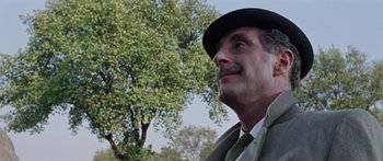 Movie still from “The Ipcress File” (1965), directed by Sidney J. Furie – An older man wearing a hat and a tie; Close Up shot, Low angle