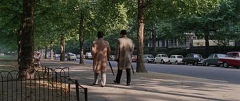 Movie still from “The Ipcress File” (1965), directed by Sidney J. Furie – Two people walking down a sidewalk near a tree; Wide shot, High angle
