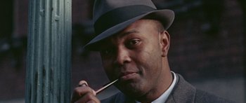 Movie still from “The Ipcress File” (1965), directed by Sidney J. Furie – A man wearing a hat and holding a pipe in his mouth; Close Up shot, Low angle