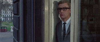 Movie still from “The Ipcress File” (1965), directed by Sidney J. Furie – A man in a suit and tie looking out of a window; Close Up shot, Low angle