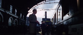 Movie still from “The Ipcress File” (1965), directed by Sidney J. Furie – A man standing in front of a train on a train platform; Wide shot, Low angle