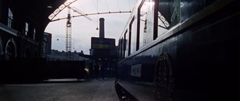 Movie still from “The Ipcress File” (1965), directed by Sidney J. Furie – A train parked in front of a building with people standing around; Extreme Wide shot, Low angle
