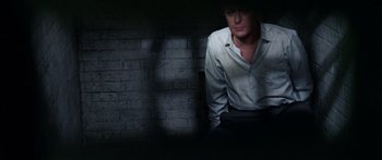 Movie still from “The Ipcress File” (1965), directed by Sidney J. Furie – A man in a white shirt is standing in the dark; Medium shot, High angle