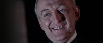 Movie still from “The Ipcress File” (1965), directed by Sidney J. Furie – A man smiling for the camera; Close Up shot, Low angle