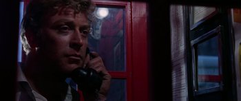 Movie still from “The Ipcress File” (1965), directed by Sidney J. Furie – A man talking on a phone in front of a red door; Close Up shot, Low angle