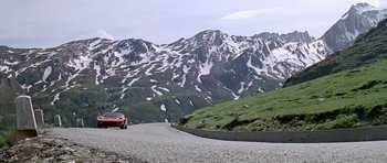 Movie still from “The Italian Job” (1969), directed by Peter Collinson – A car driving down a road in the mountains; Extreme Wide shot, Low angle