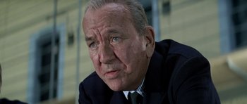 Movie still from “The Italian Job” (1969), directed by Peter Collinson – An older man in a suit and tie looking sad; Close Up shot, Low angle