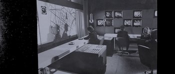 Movie still from “The Italian Job” (1969), directed by Peter Collinson – A woman sitting at a table in front of a map; Wide shot, High angle