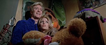 Movie still from “The Italian Job” (1969), directed by Peter Collinson – A man and a woman sitting next to a teddy bear; Medium shot, Low angle