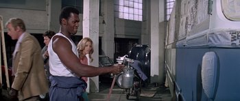 Movie still from “The Italian Job” (1969), directed by Peter Collinson – A man and a woman in a garage with a spray gun; Medium shot, Low angle