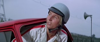 Movie still from “The Italian Job” (1969), directed by Peter Collinson – A man wearing a helmet sitting in a red car; Close Up shot, Low angle