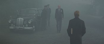 Movie still from “The Italian Job” (1969), directed by Peter Collinson – A group of men standing next to each other in the fog; Wide shot, Over the shoulder angle