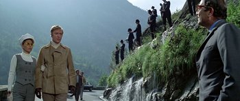Movie still from “The Italian Job” (1969), directed by Peter Collinson – A group of men standing on a hill next to a waterfall; Extreme Wide shot, Low angle
