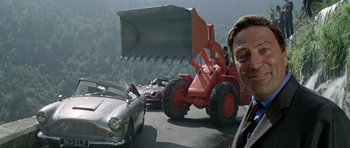 Movie still from “The Italian Job” (1969), directed by Peter Collinson – A man standing in front of a car and a tractor; Medium shot, Low angle