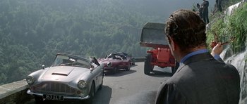 Movie still from “The Italian Job” (1969), directed by Peter Collinson – A man standing next to cars on a road; Wide shot, Over the shoulder angle