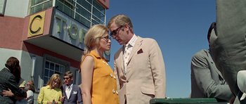 Movie still from “The Italian Job” (1969), directed by Peter Collinson – A man and a woman standing next to each other; Medium shot, Low angle
