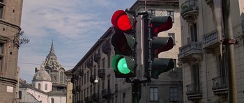 Movie still from “The Italian Job” (1969), directed by Peter Collinson – A red and green traffic light sitting on the side of a road; Wide shot, Low angle