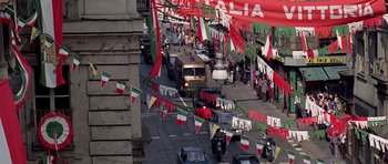 Movie still from “The Italian Job” (1969), directed by Peter Collinson – An overhead view of a street with many flags; Extreme Wide shot, High angle