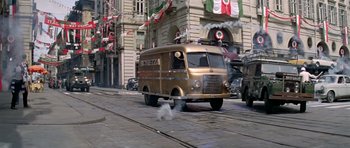 Movie still from “The Italian Job” (1969), directed by Peter Collinson – An old van driving down a street past a building; Wide shot, High angle