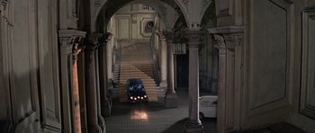 Movie still from “The Italian Job” (1969), directed by Peter Collinson – A car driving down the middle of a staircase in a building; Extreme Wide shot, High angle