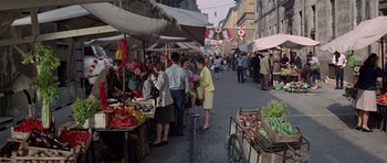 Movie still from “The Italian Job” (1969), directed by Peter Collinson – A group of people standing around a market; Wide shot, High angle