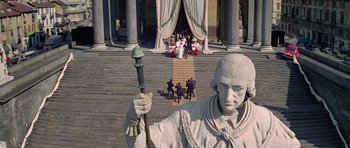 Movie still from “The Italian Job” (1969), directed by Peter Collinson – A group of people standing around a statue; Extreme Wide shot, Low angle