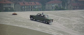Movie still from “The Italian Job” (1969), directed by Peter Collinson – An old car is driving down the street; Extreme Wide shot, High angle