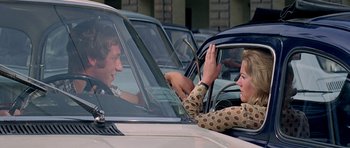 Movie still from “The Italian Job” (1969), directed by Peter Collinson – Two people sitting in the drivers seat of a parked car; Medium shot, Over the shoulder angle