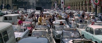 Movie still from “The Italian Job” (1969), directed by Peter Collinson – A large group of people are in the middle of a busy street; Extreme Wide shot, High angle