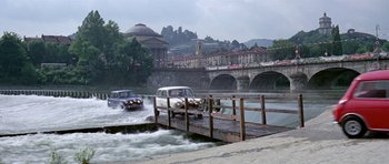 Movie still from “The Italian Job” (1969), directed by Peter Collinson – Two cars are driving on a bridge over a river; Extreme Wide shot, High angle