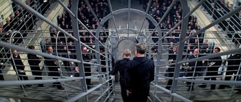 Movie still from “The Italian Job” (1969), directed by Peter Collinson – A group of men standing around in a cage; Wide shot, High angle
