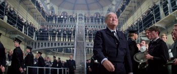Movie still from “The Italian Job” (1969), directed by Peter Collinson – An older man in a suit and tie in front of a crowd; Medium shot, Low angle