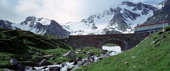 Movie still from “The Italian Job” (1969), directed by Peter Collinson – A stone bridge over a river in the mountains; Extreme Wide shot, High angle