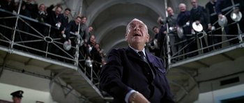 Movie still from “The Italian Job” (1969), directed by Peter Collinson – An older man in a suit and tie laughing; Medium shot, Low angle