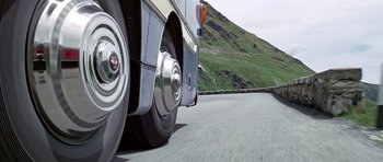 Movie still from “The Italian Job” (1969), directed by Peter Collinson – The front tire of a tour bus; Wide shot, Low angle