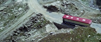 Movie still from “The Italian Job” (1969), directed by Peter Collinson – A red and blue bus driving down a road; Extreme Wide shot, Overhead angle