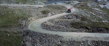 Movie still from “The Italian Job” (1969), directed by Peter Collinson – An aerial view of a truck driving down a mountain road; Extreme Wide shot, High angle