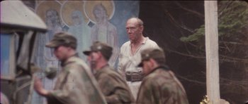 Movie still from “The Keep” (1983), directed by Michael Mann – An old man in a white shirt and some soldiers; Medium shot, Over the shoulder angle