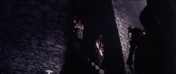 Movie still from “The Keep” (1983), directed by Michael Mann – Two men are climbing up a set of stairs; Wide shot, Low angle