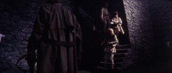 Movie still from “The Keep” (1983), directed by Michael Mann – A group of people standing on some stairs; Wide shot, High angle