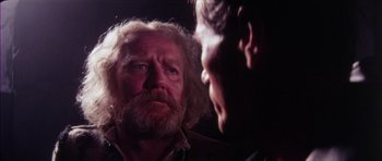 Movie still from “The Keep” (1983), directed by Michael Mann – A man with a beard is looking at another man with a beard; Close Up shot, Over the shoulder angle