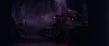 Movie still from “The Keep” (1983), directed by Michael Mann – A person walking in the dark near a bench; Extreme Wide shot, High angle