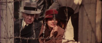 Movie still from “The Keep” (1983), directed by Michael Mann – A group of people sitting next to each other wearing hats; Close Up shot, Over the shoulder angle