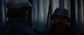 Movie still from “The Keep” (1983), directed by Michael Mann – A man in a helmet is holding a rifle; Close Up shot, Over the shoulder angle